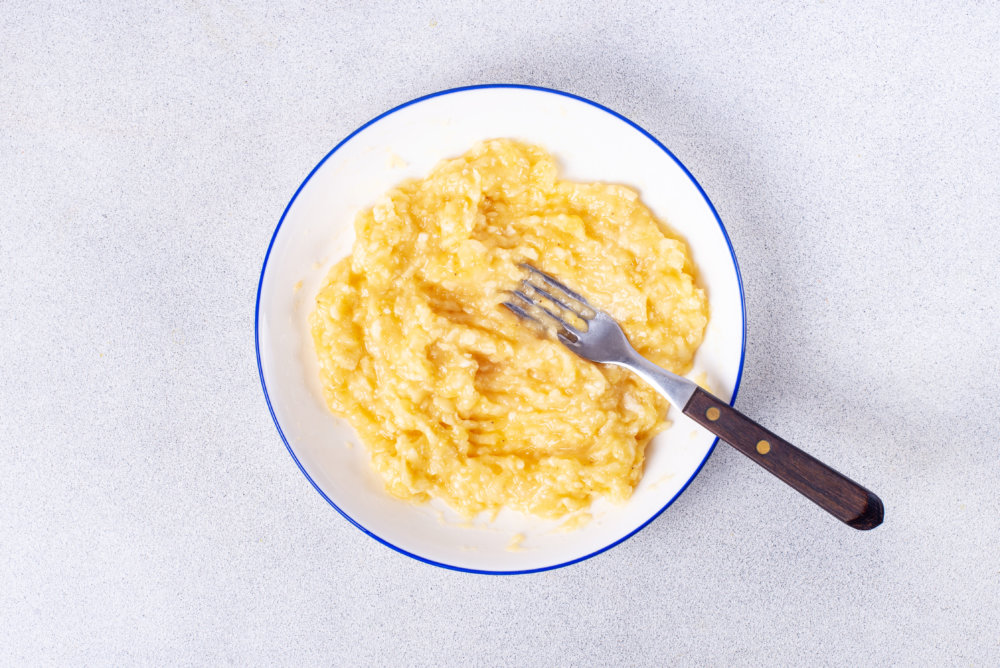 a plate with mashed bananas and a fork.