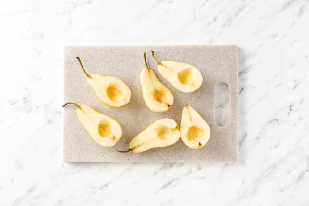 a cutting board with halved pears on it.