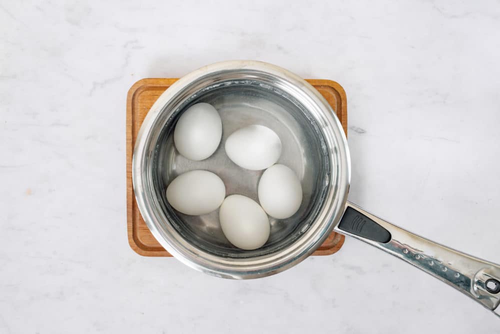 hard boiled eggs in a silver pot on a wooden board.