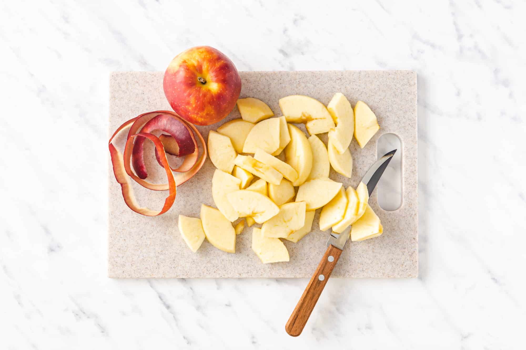 peeled and chopped apple on a cutting board with a knife.