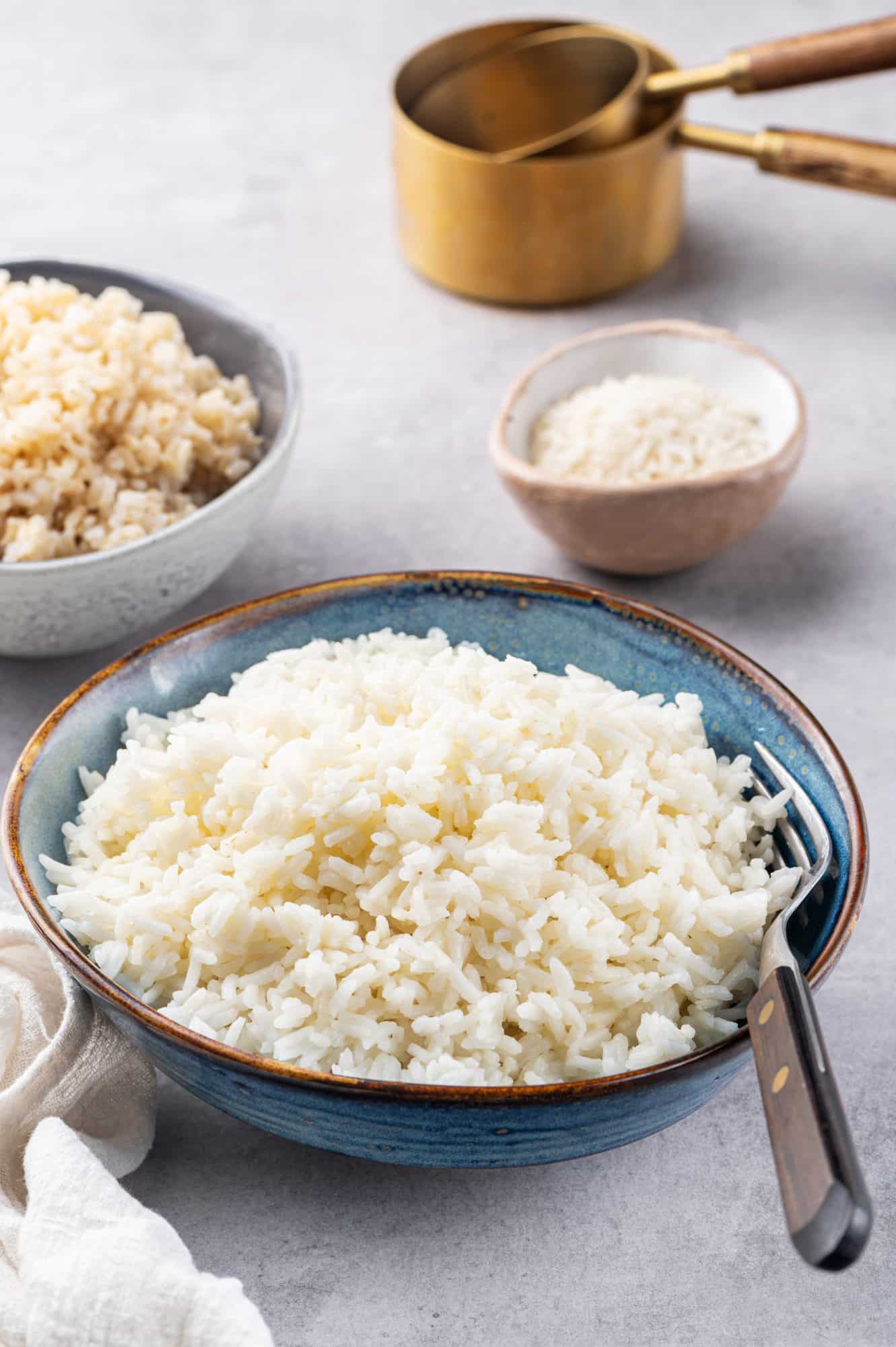 White rice in a blue bowl with a fork on the side.