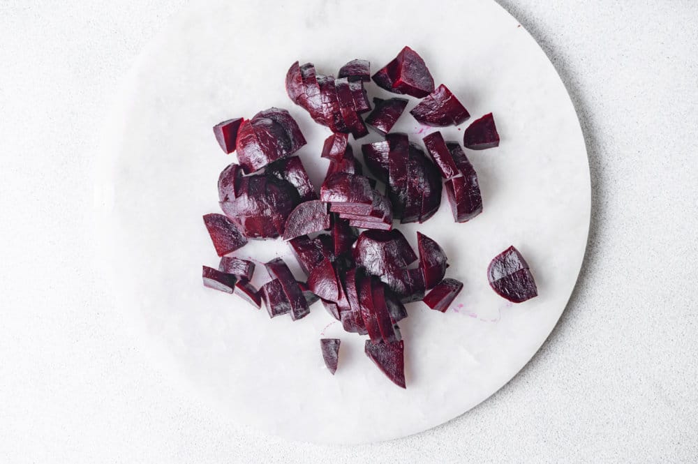 roasted chopped beets on a white plate.