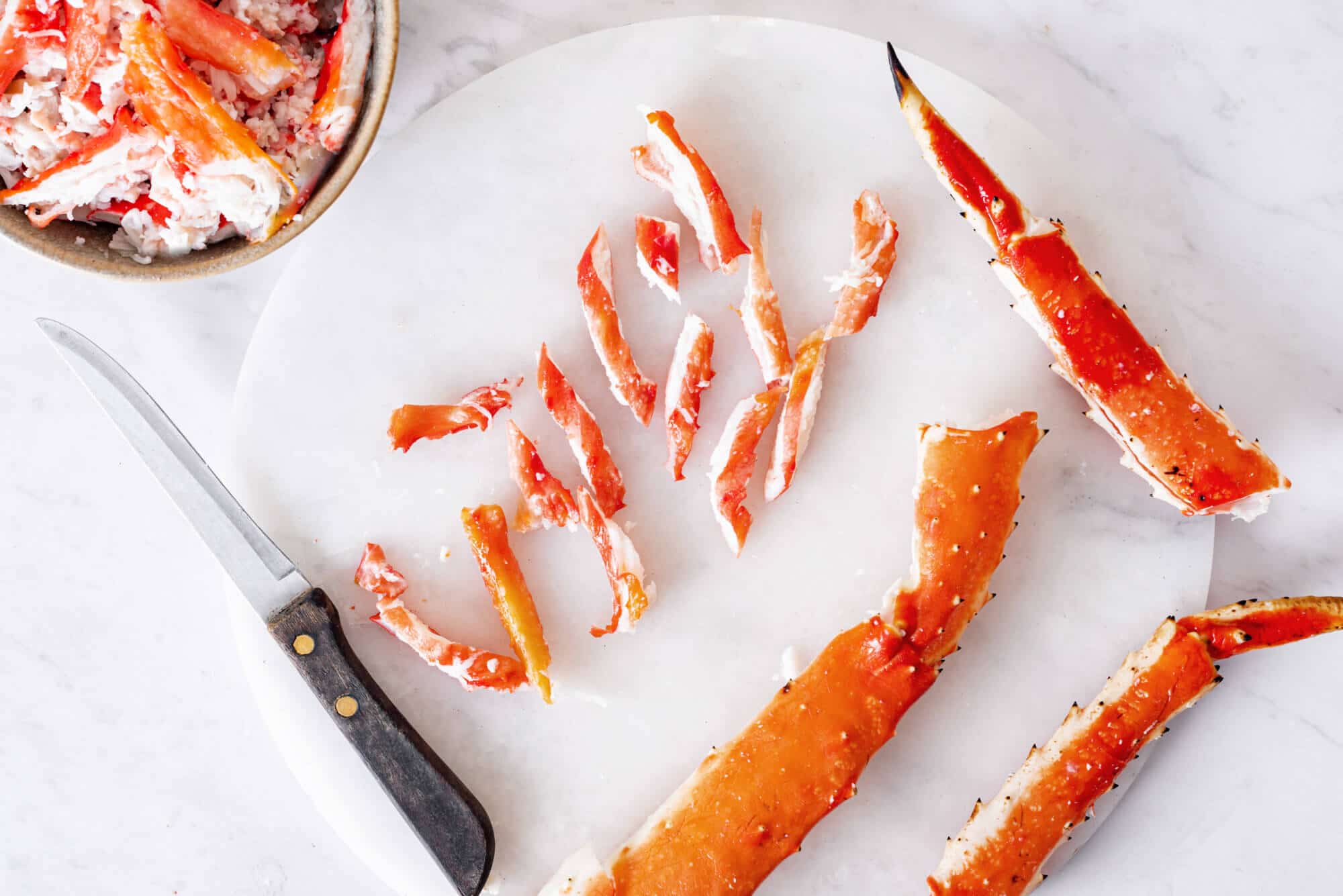 Chopped crab legs on a cutting board with a knife.