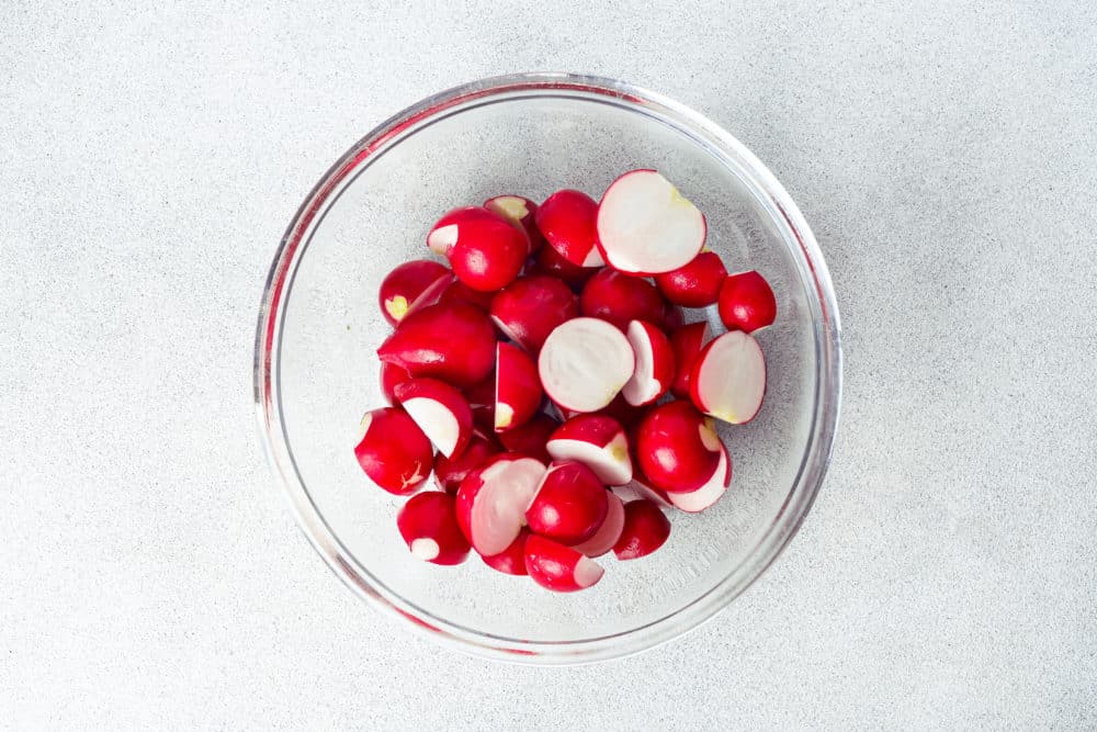 a bowl of washed and cut radishes.