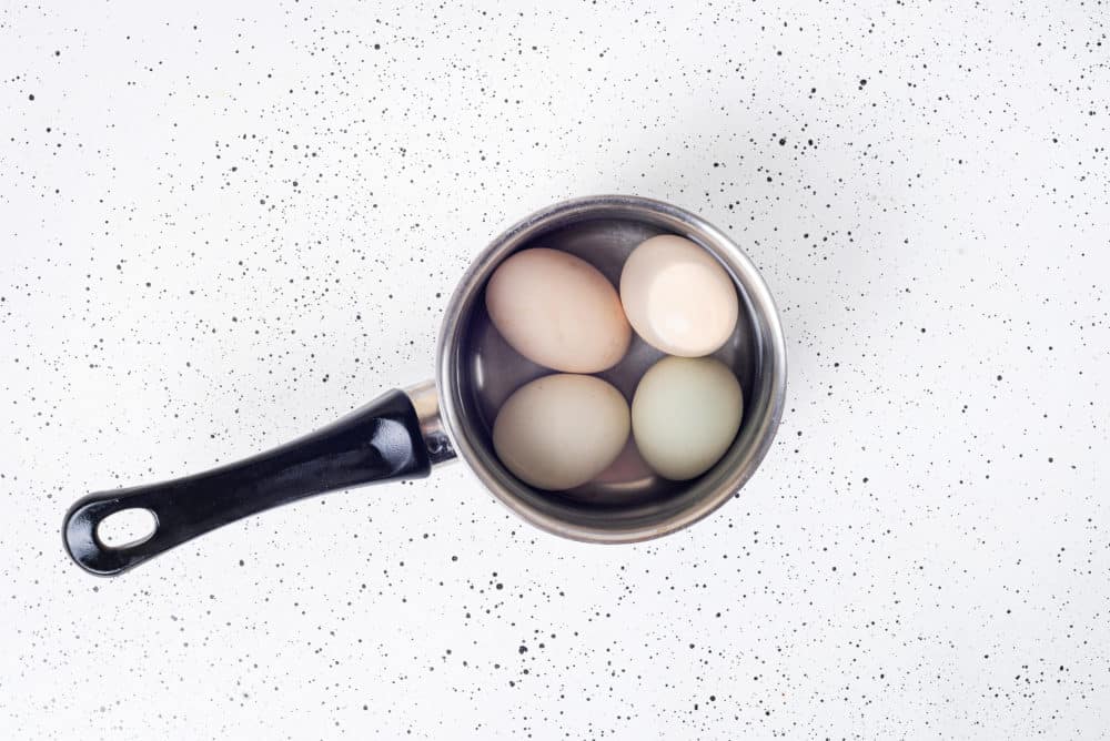 Eggs boiled in a silver pot with water.