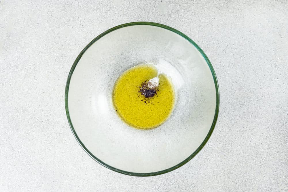 Olive oil, salt, and pepper in a glass bowl.