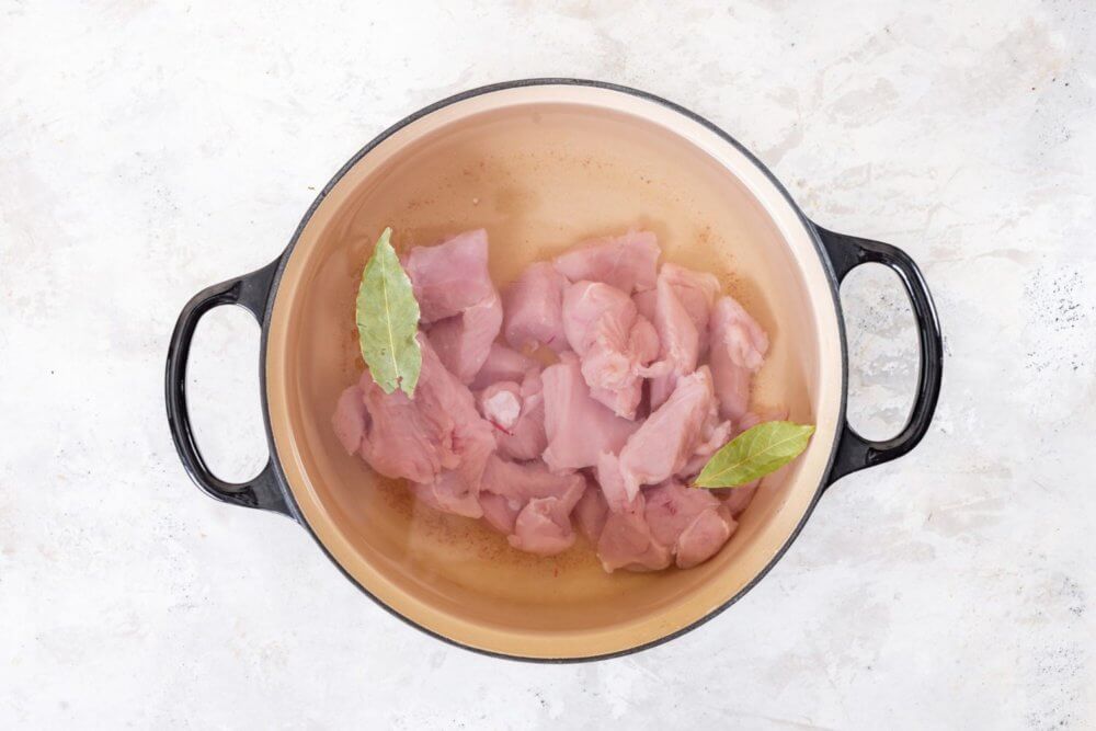 Chicken and bay leaves in a pot of water.