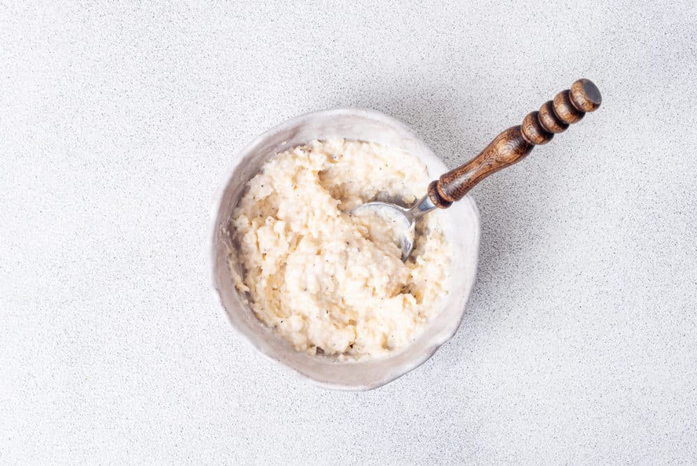 parmesan mix in a white bowl with a spoon.