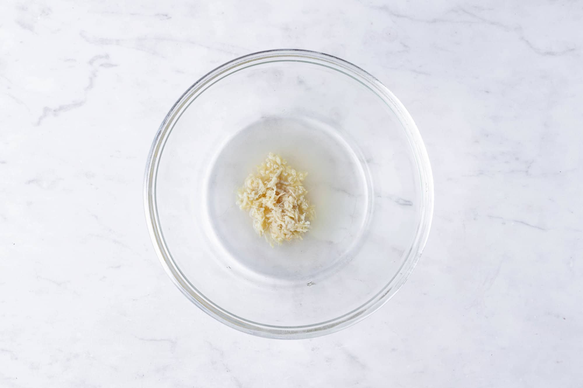 Glass bowl of honey, ginger, and water.