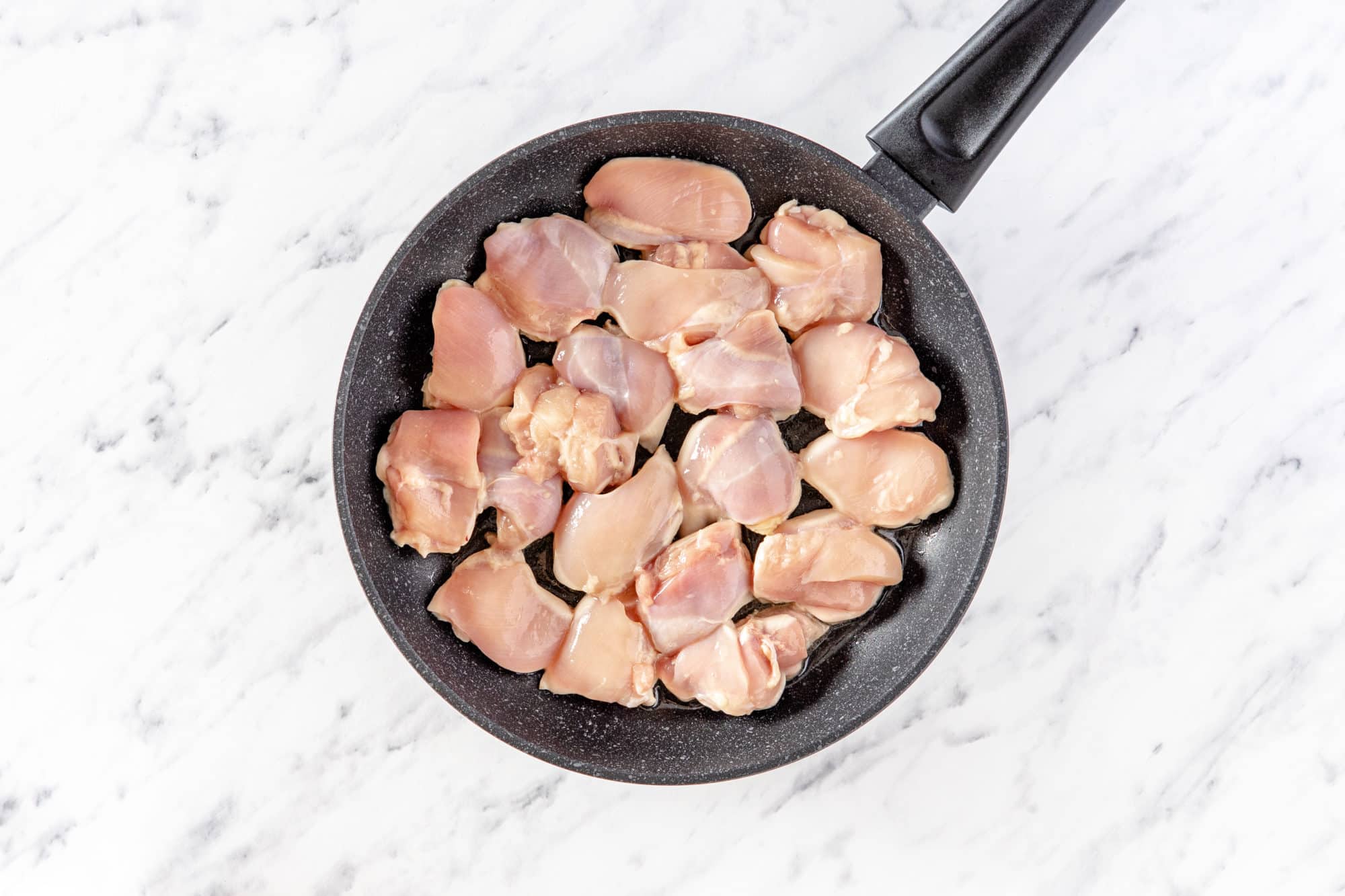 boneless skinless chicken thighs in a black pan.