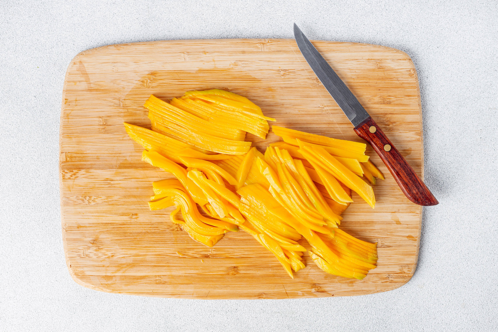 Chopped mango on a cutting board with a knife.