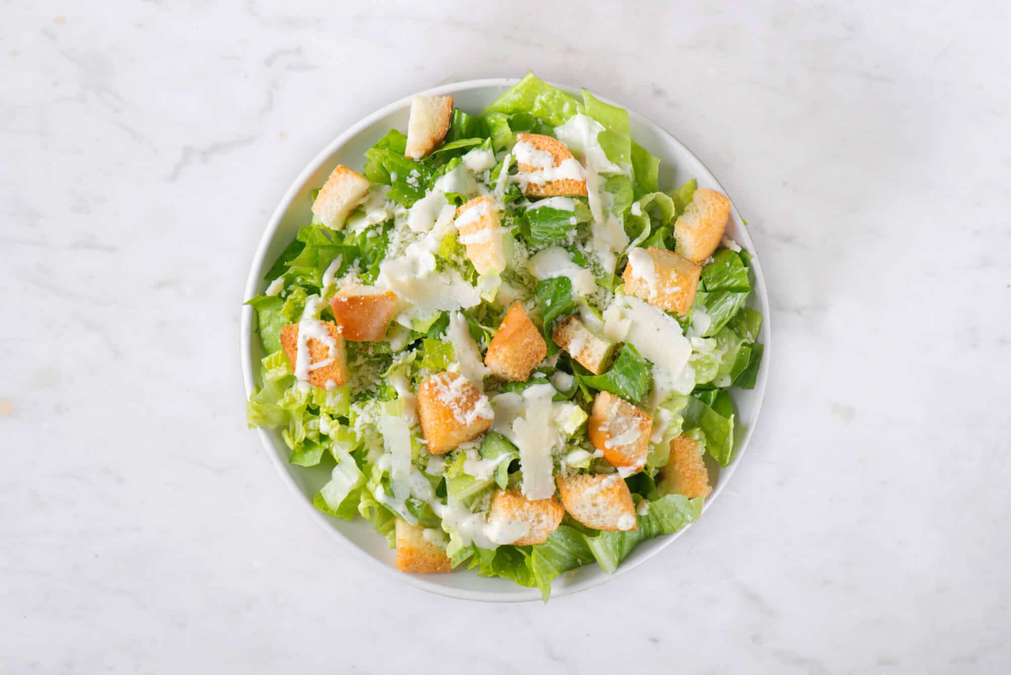 Homemade caesar salad on a white plate.