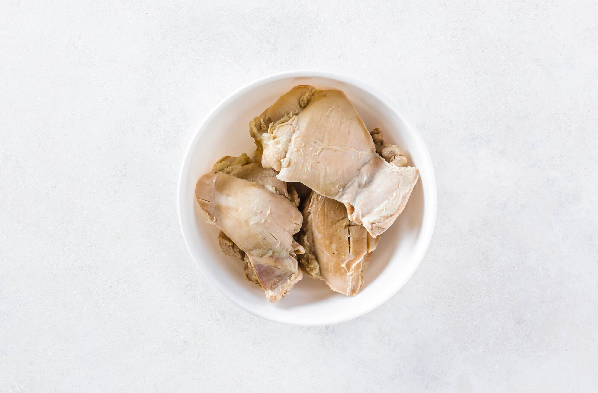 Cooked chicken thighs in a white bowl.