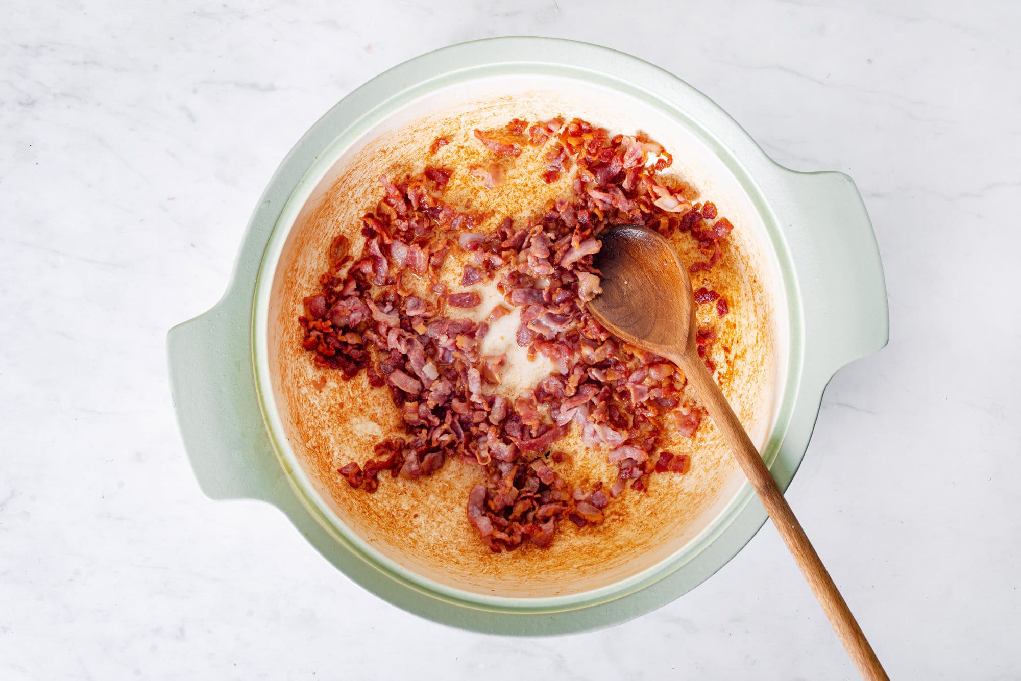 bacon-sauteing-in-a-skillet-with-a-wooden-spoon