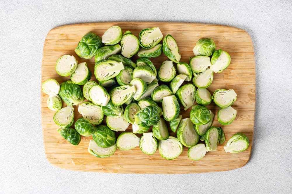 a wooden cutting board with chopped brussels sprouts on it.