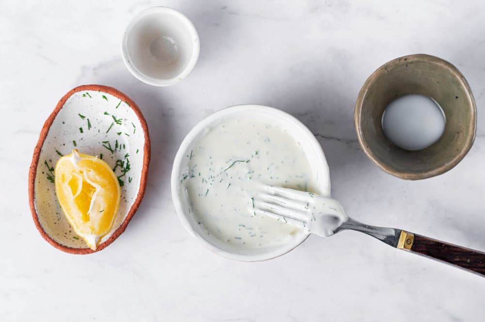 Dressing for turkey salad in a white bowl, with empty ingredient bowls on the side.