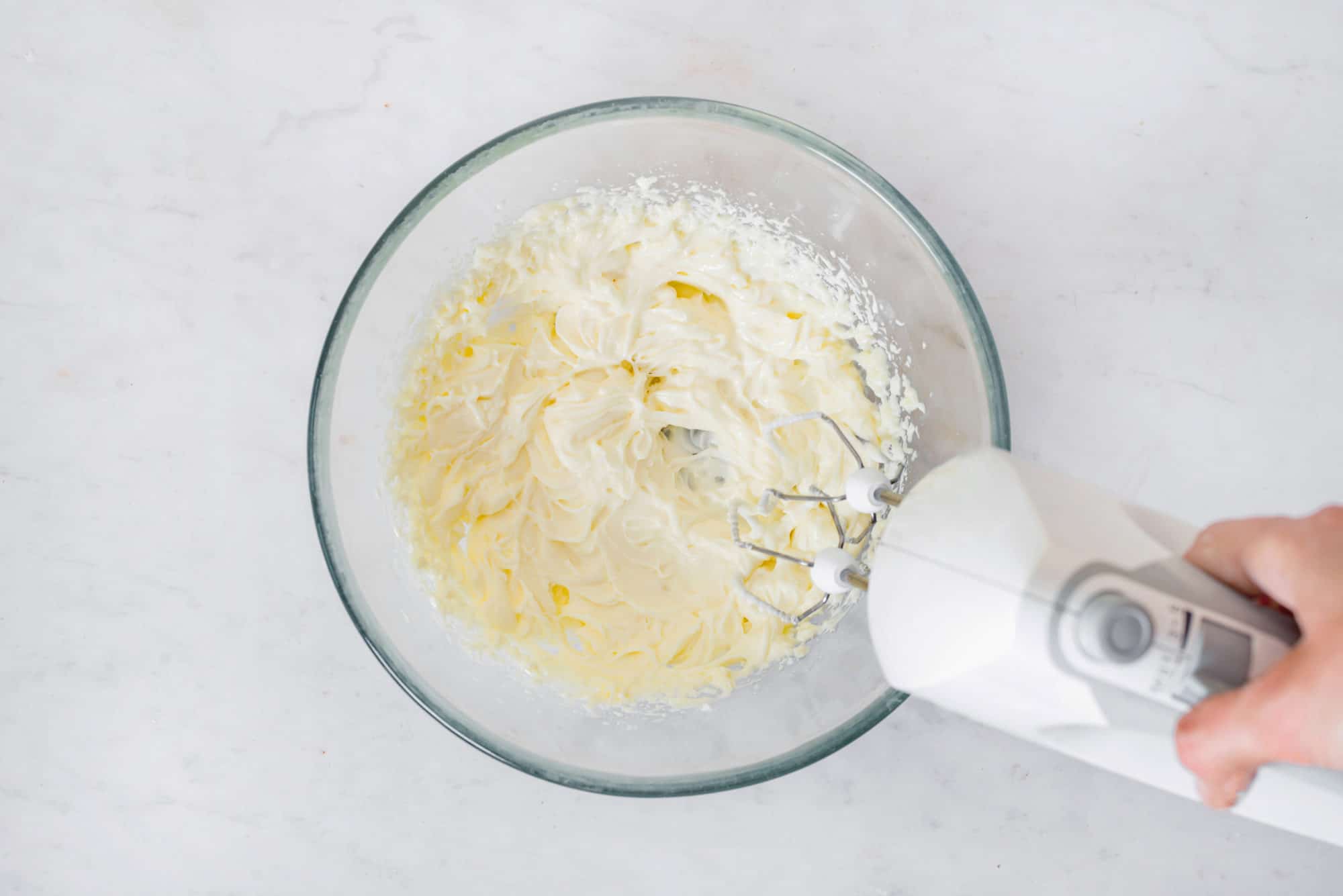 cheesecake-filling-in-a-clear-bowl-with-a-hand-mixer