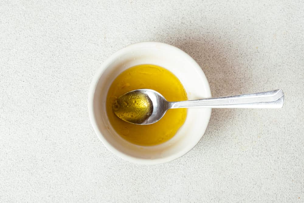 yellow salad dressing in a small white bowl with a spoon.