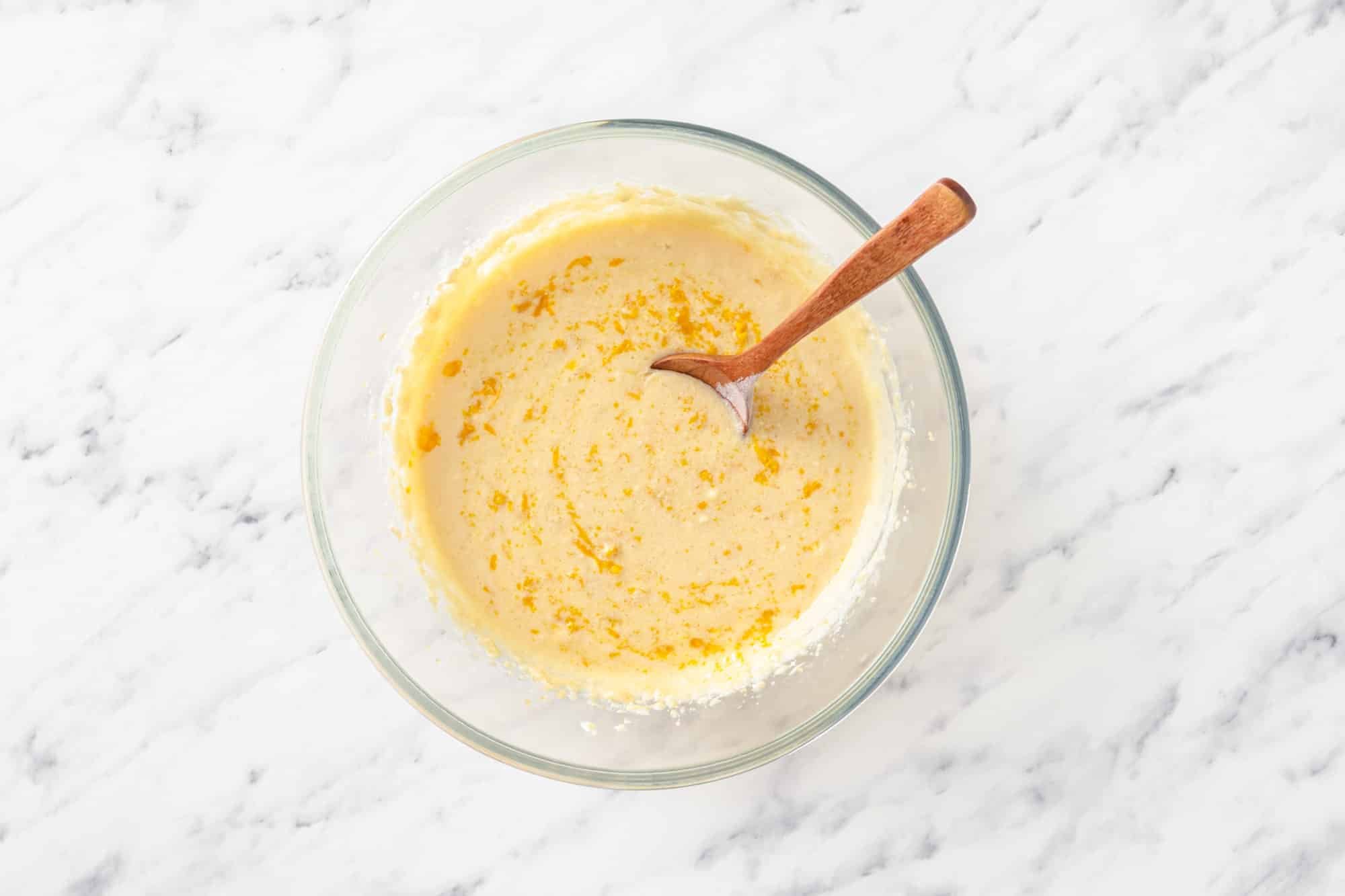 wet ingredients in a glass bowl with a wooden spoon.