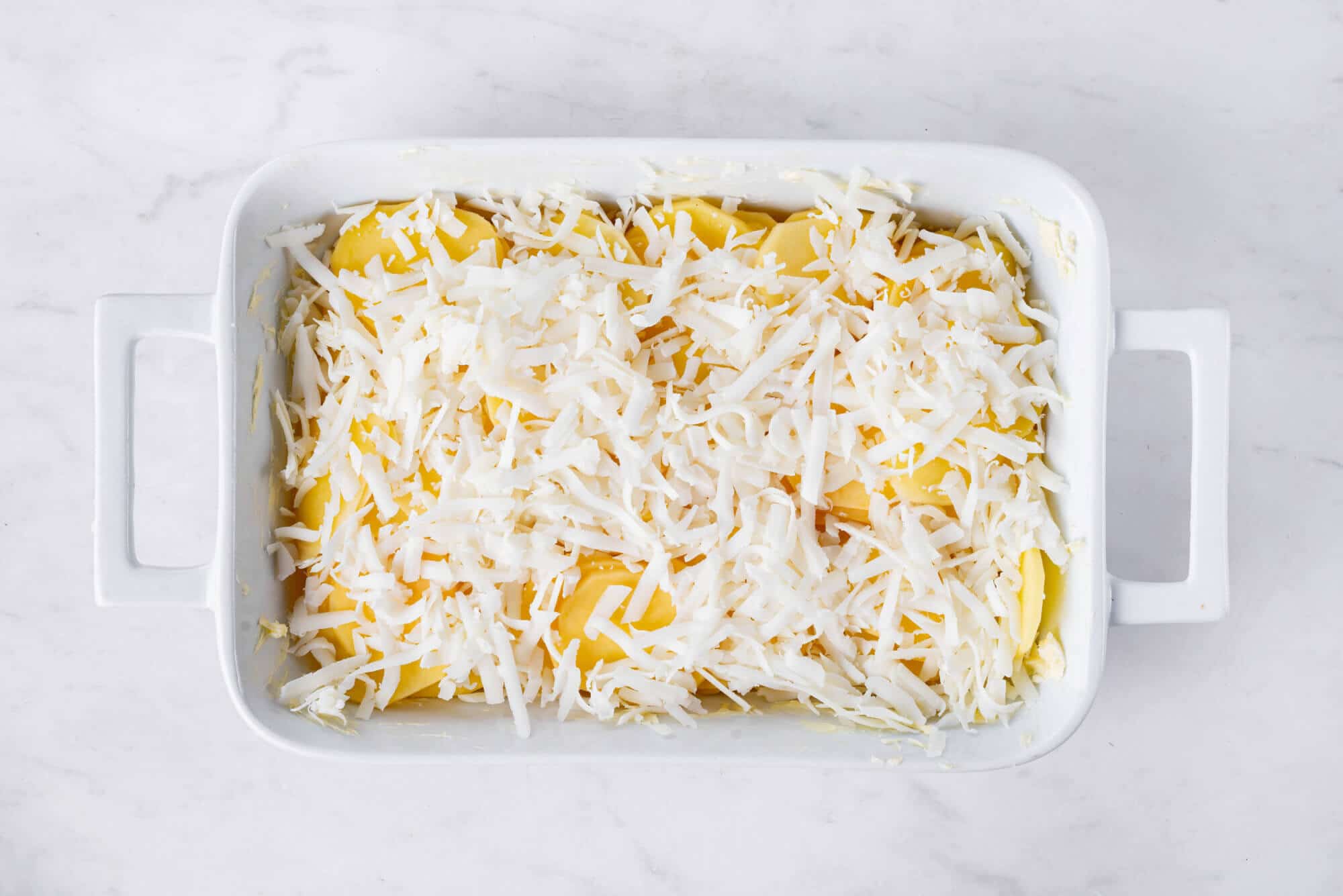 scalloped-potatoes-covered-in-cheese-unbaked-in-a-baking-dish.