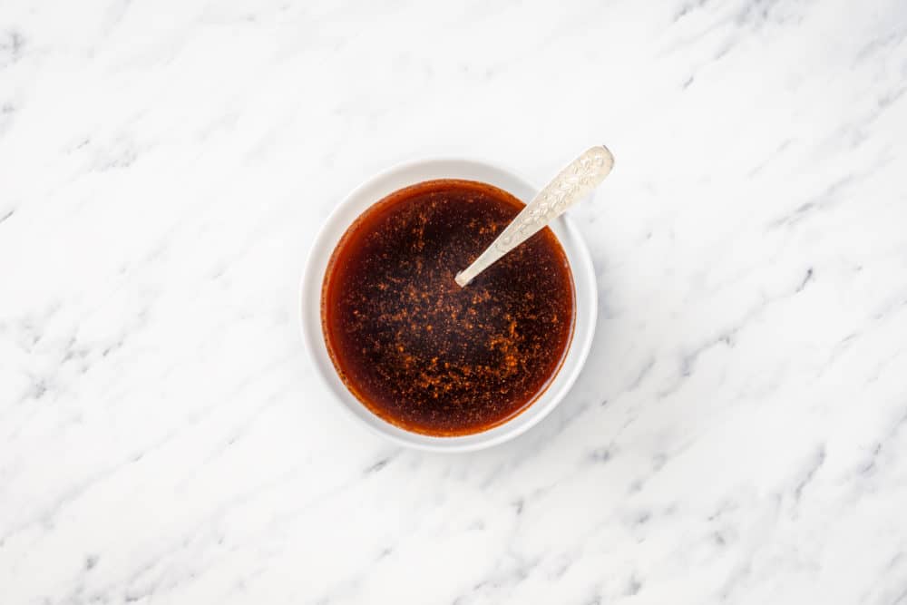 a white bowl with liquid honey spice mix with a spoon.