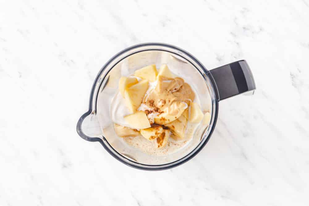 ingredients for an apple smoothie in a blender.