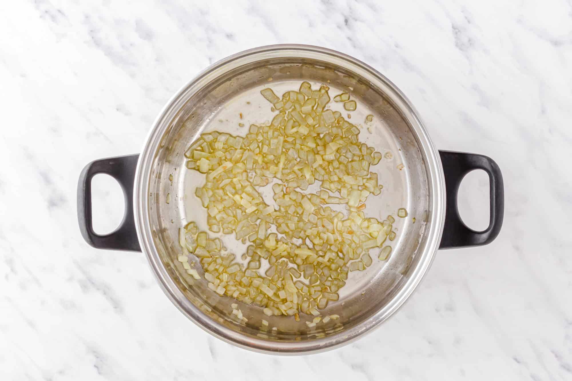 chopped onion sauteing in a soup pot.