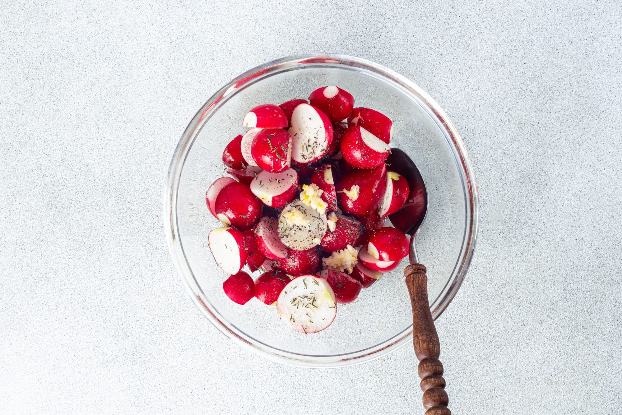 spices in a glass bowl with radishes and a spoon.