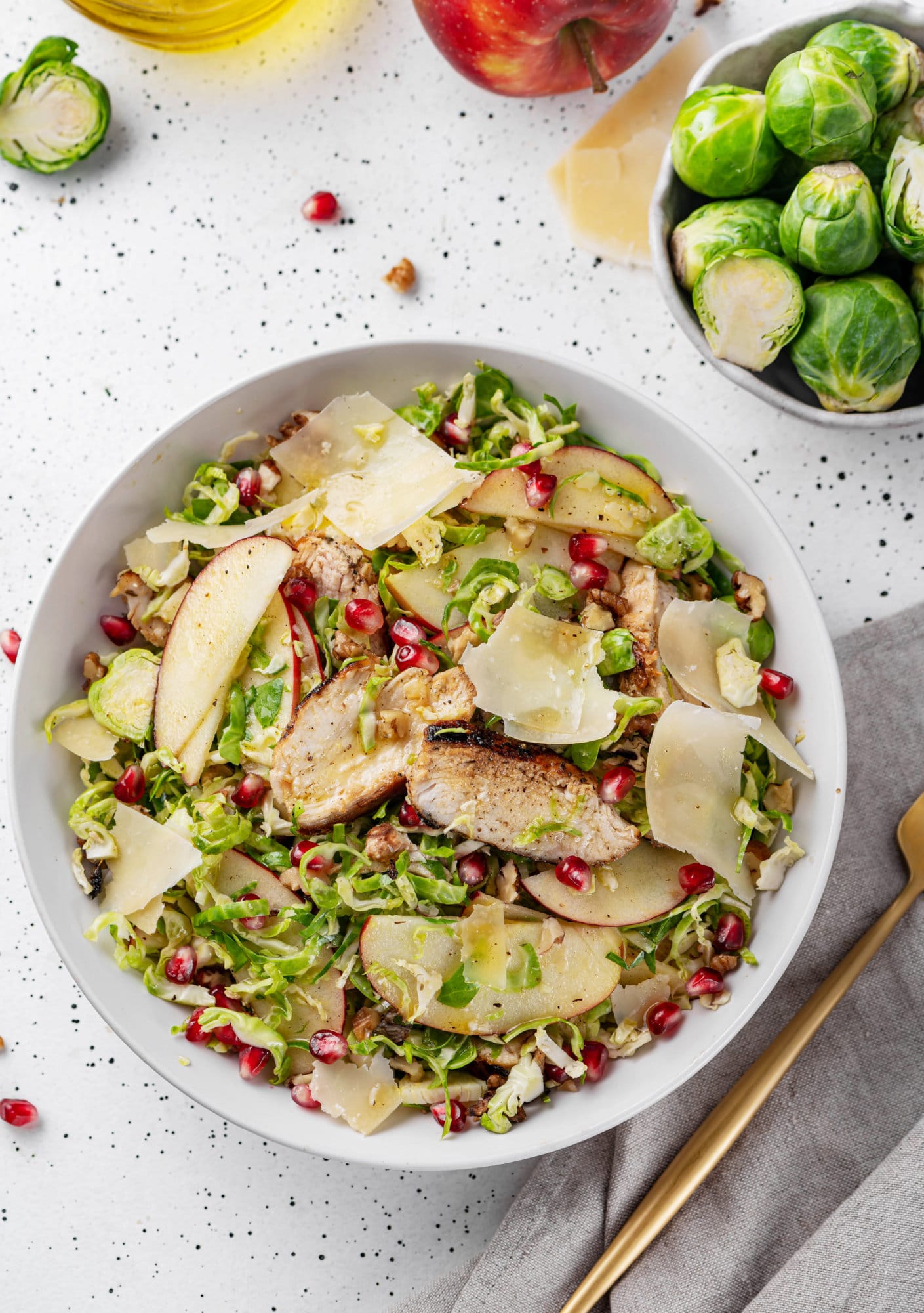 A bowl of brussels sprouts salad with more sprouts on the side.