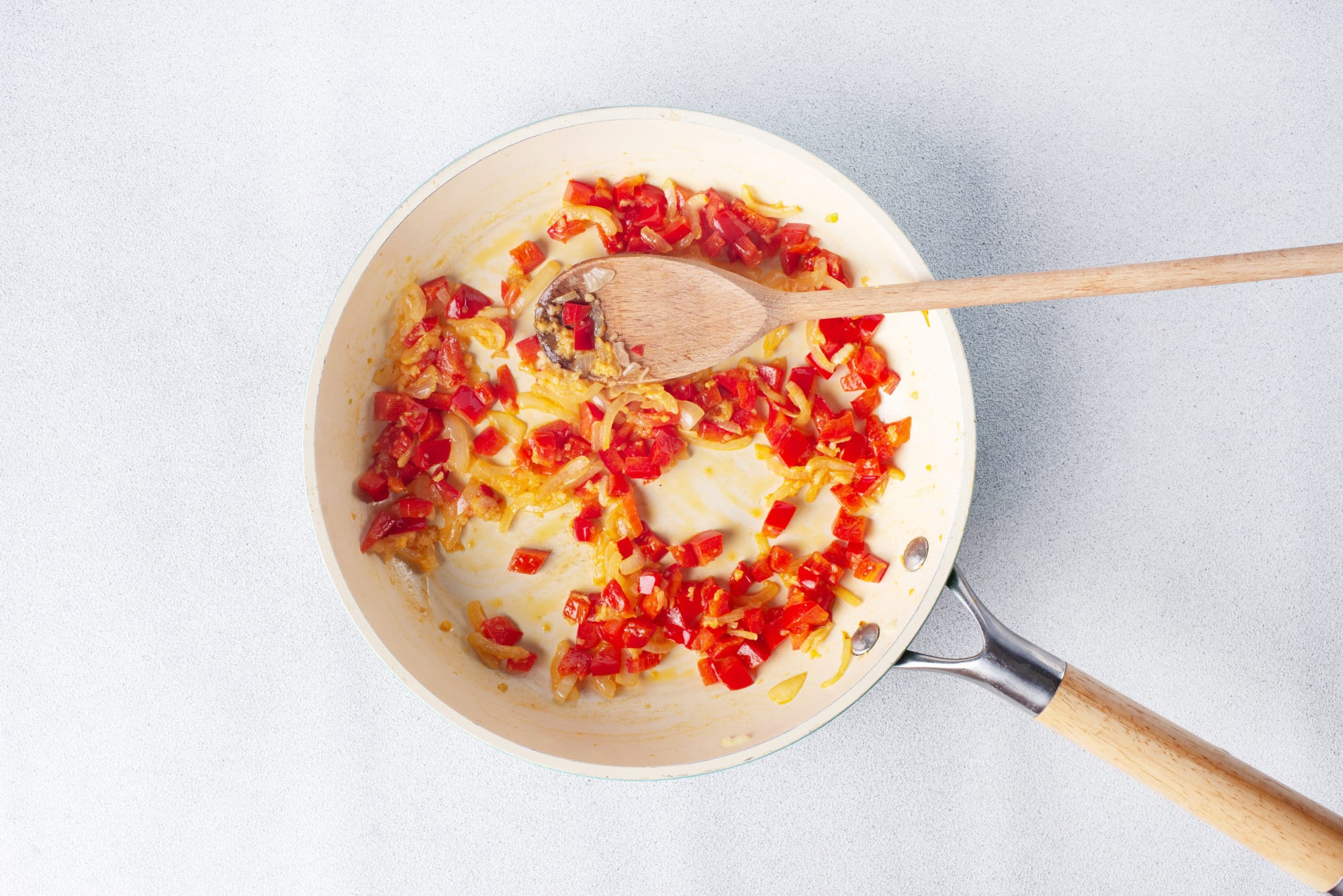 chopped onion and red bell peppers in a skillet with oil.