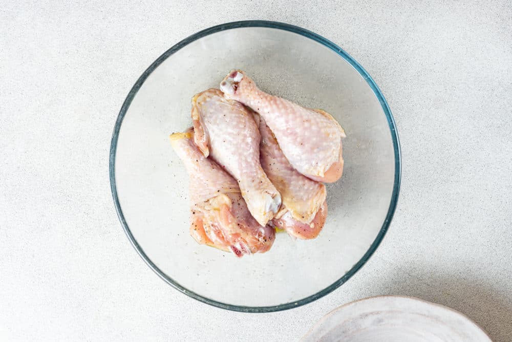 Chicken drumsticks in a glass bowl.