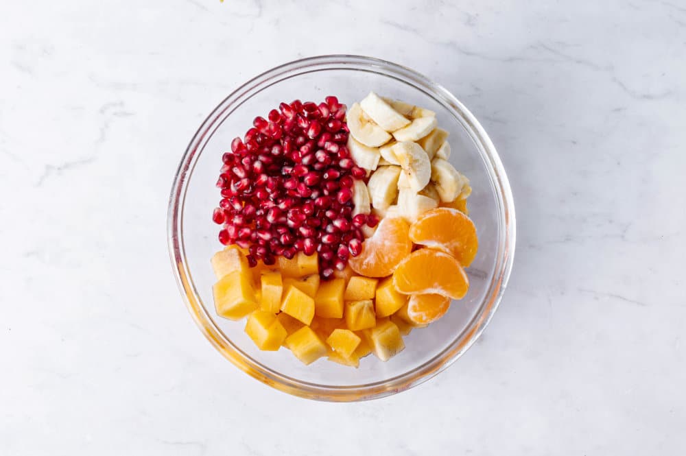 Persimmon fruit salad ingredients in a glass bowl.