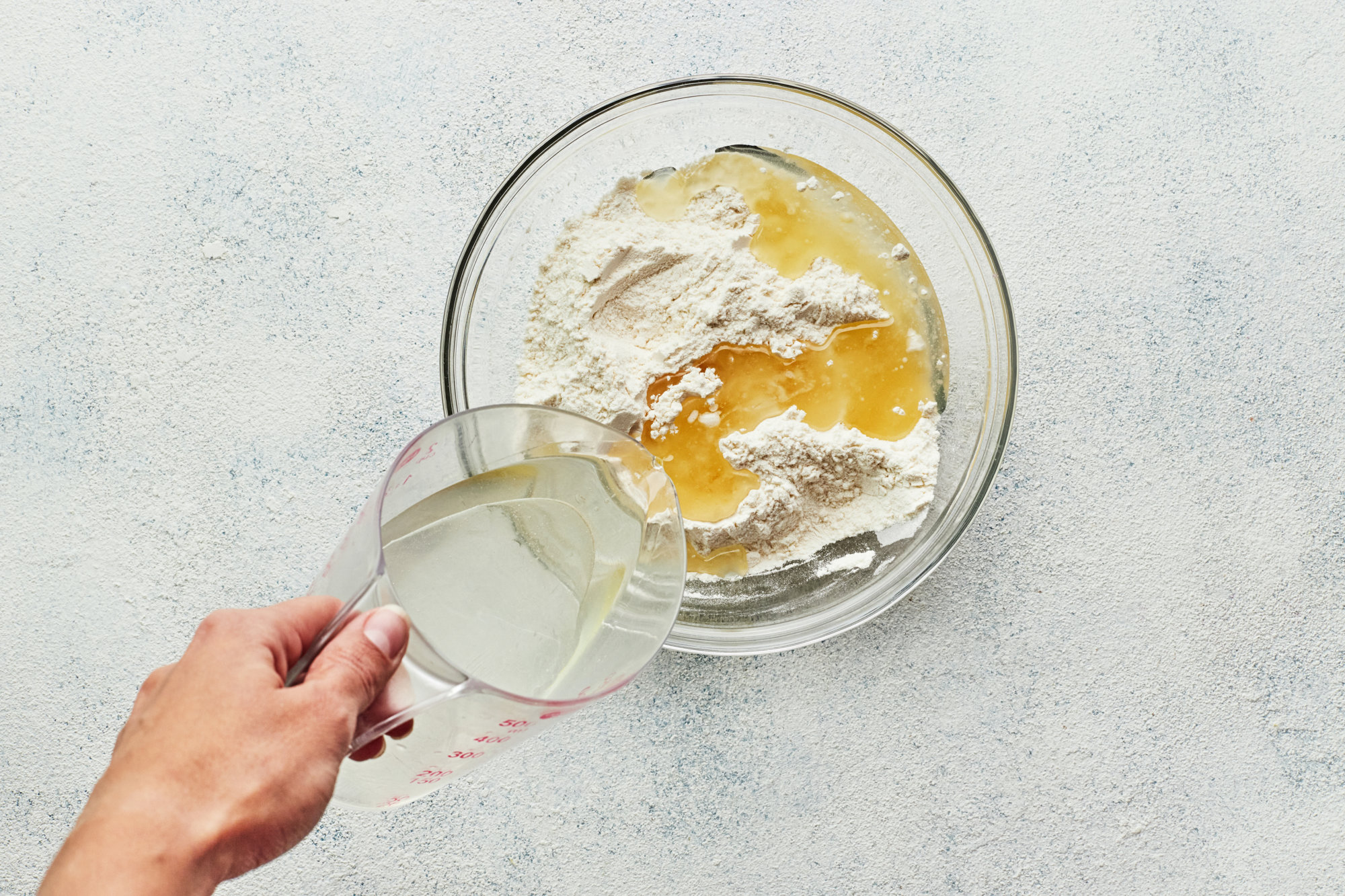 dry and wet ingredients mixing in a glass bowl.