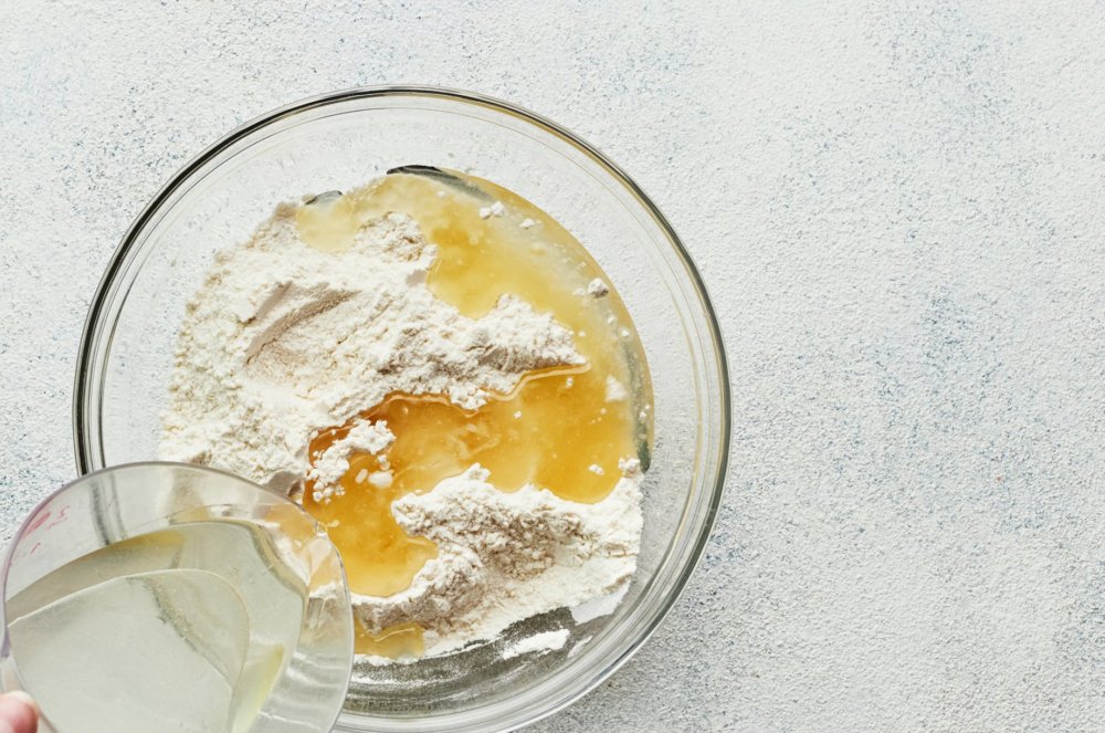 dry and wet ingredients mixing in a glass bowl.