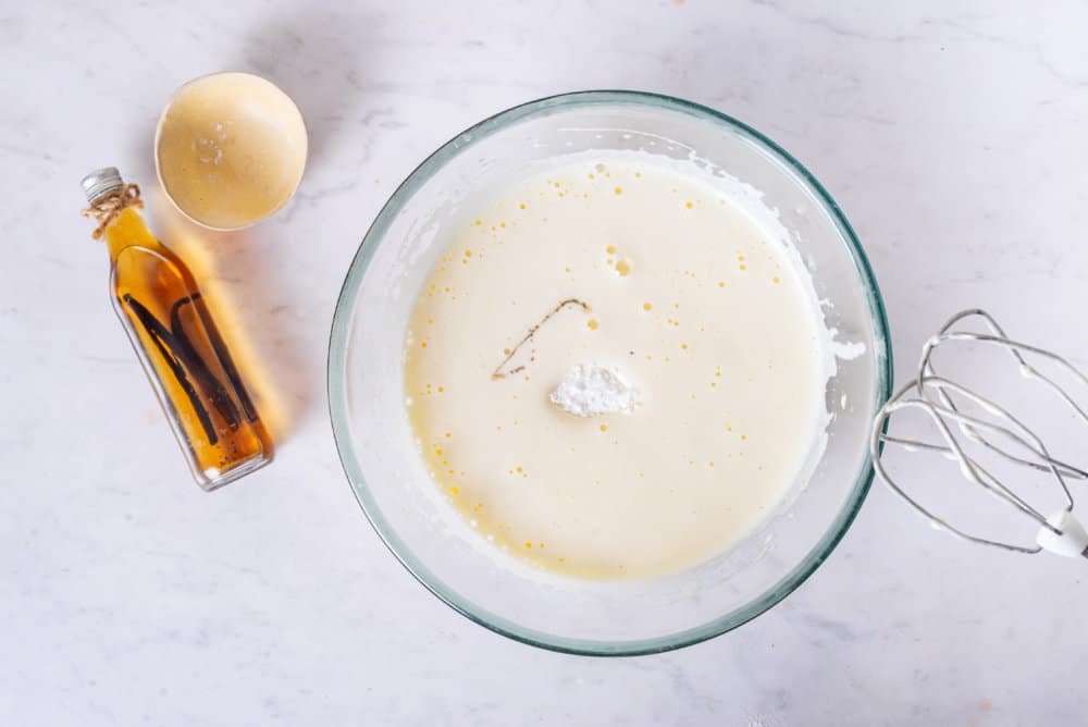 apple-cake-dough-in-a-clear-bowl-with-a-hand-mixer-and-vanilla-on-the-side