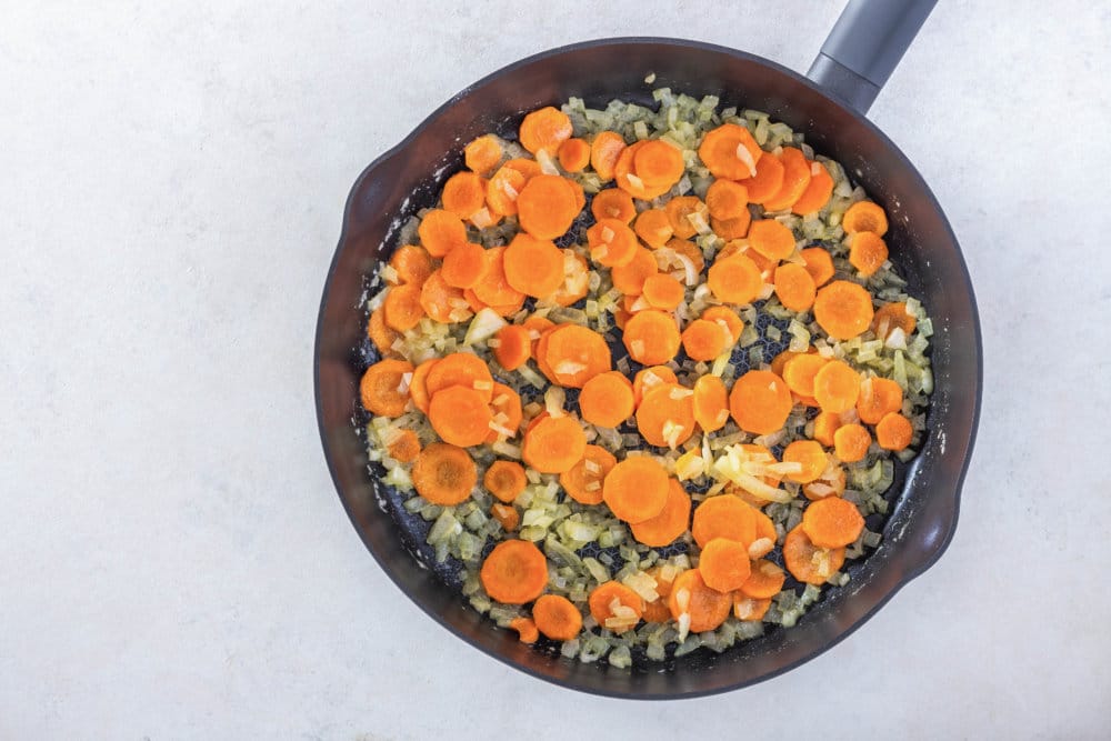 veggies sauteing in a black skillet.