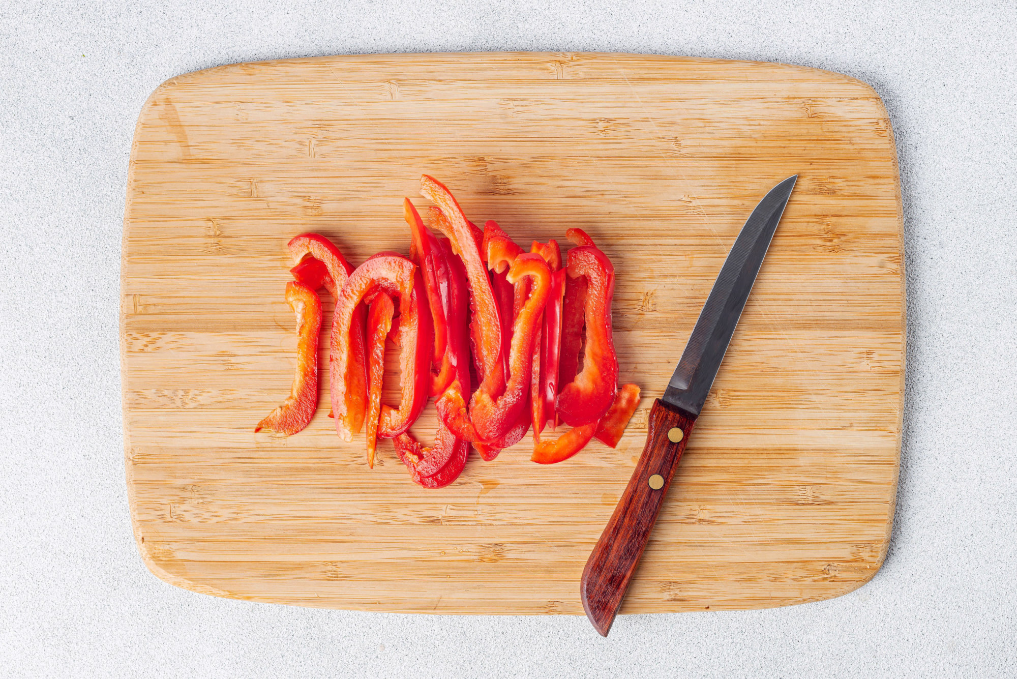 Chopped red pepper on a cutting board with a knife.