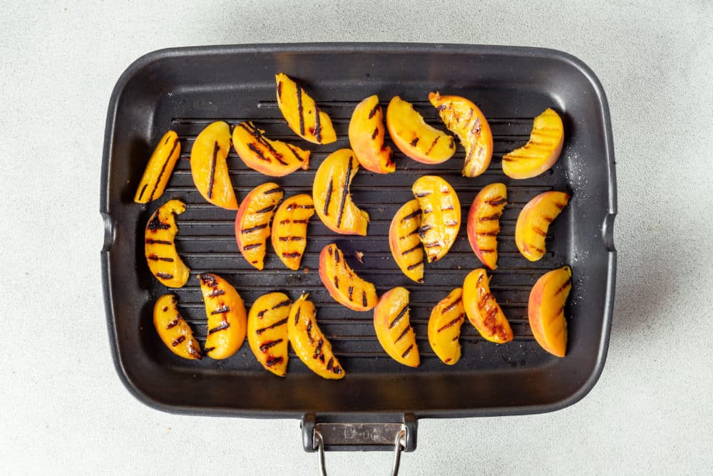 grilled peach slices on a black grill.