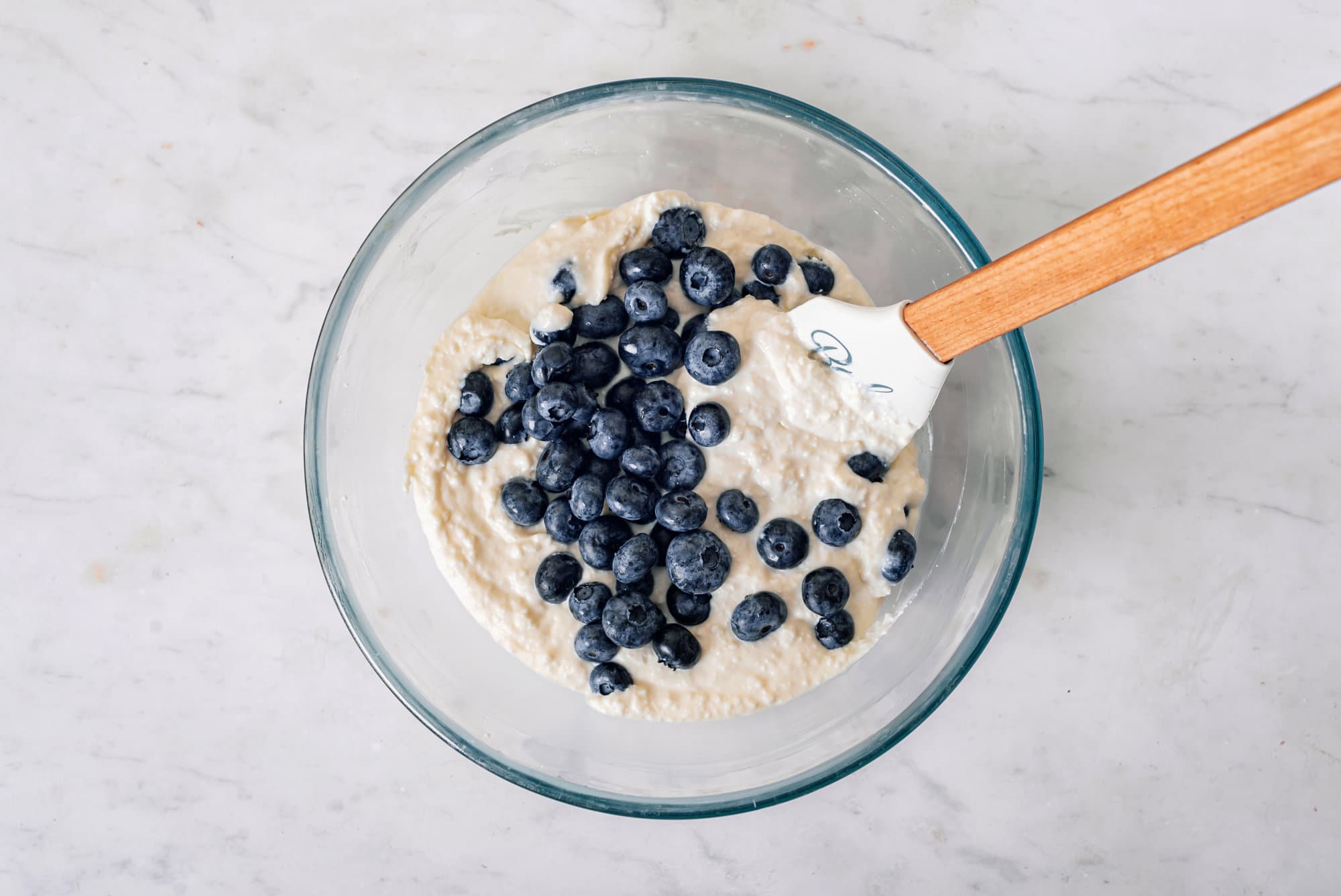 A bowl of cheese cake batter with fresh blueberries on top.