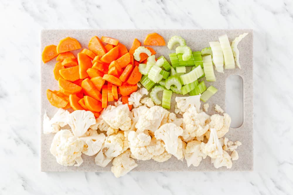 chopped vegetables on a cutting board cauliflower celery and carrots.