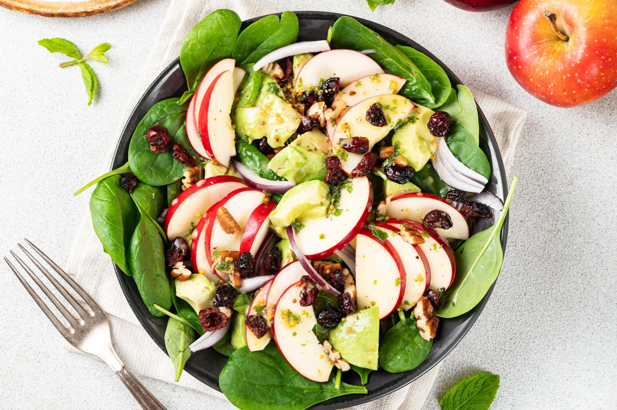 A bowl of apple, spinach, avocado salad.