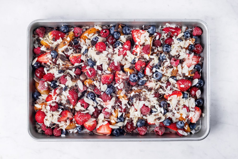 warm fruit salad on a baking sheet topped with almonds.