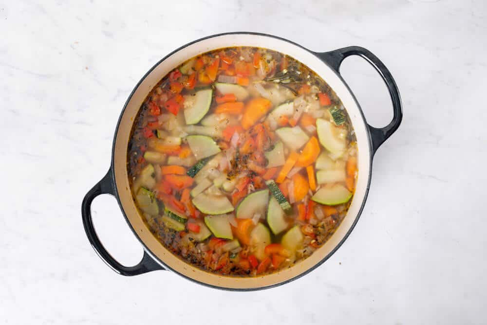 vegetables cooking in a pot with chicken broth.