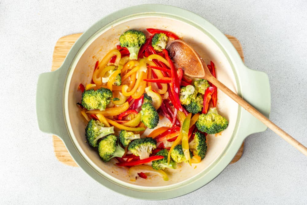 fresh veggies in a pot on a wooden board.