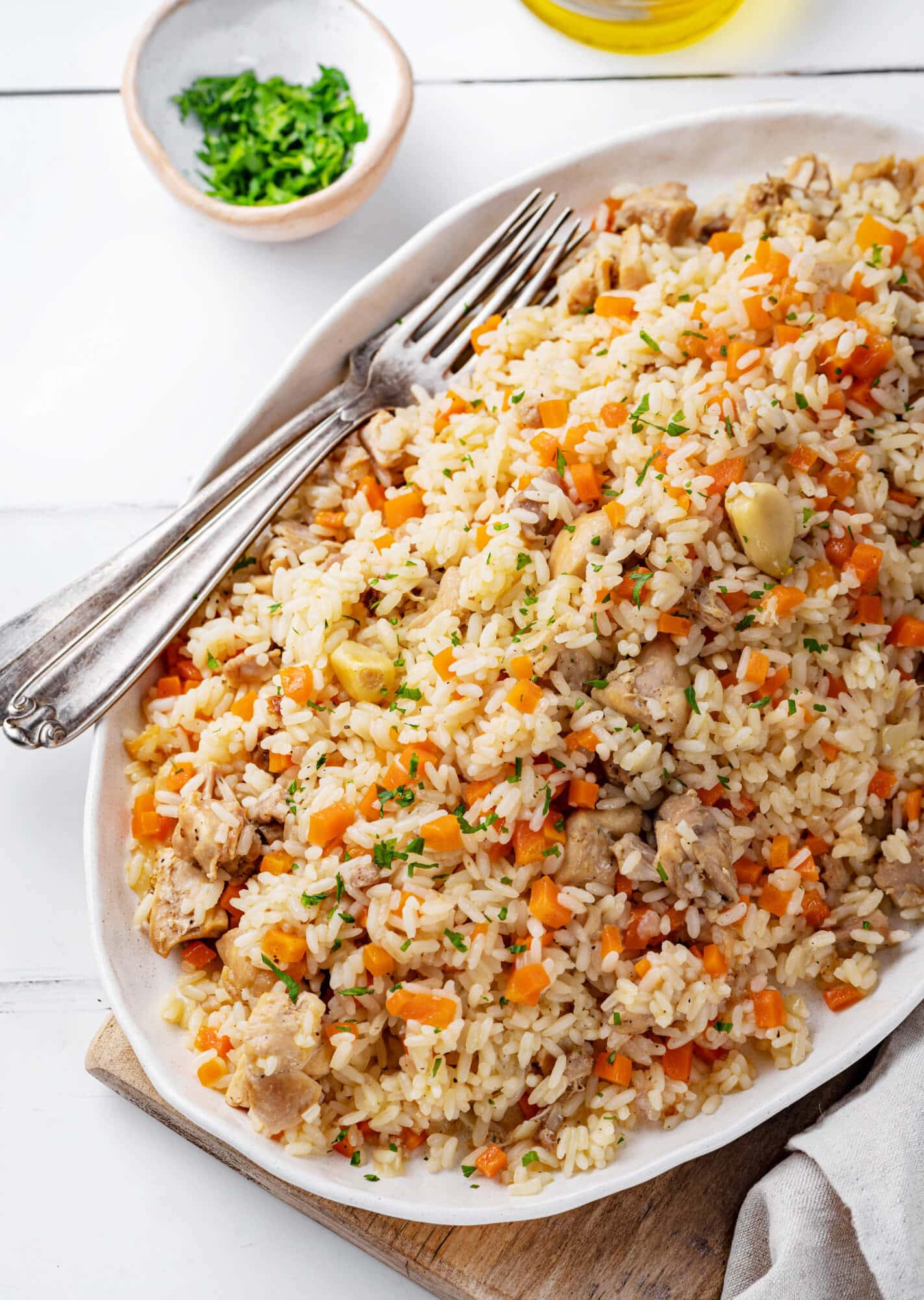 Mound of rice plov on a white plate with forks on the side.