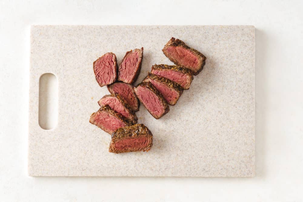 sliced cooked filet mignon on a cutting board.