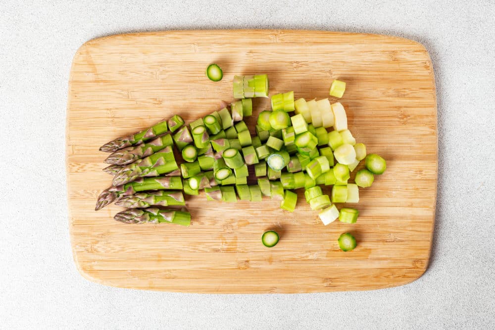 a wooden cutting board with chopped asparagus.