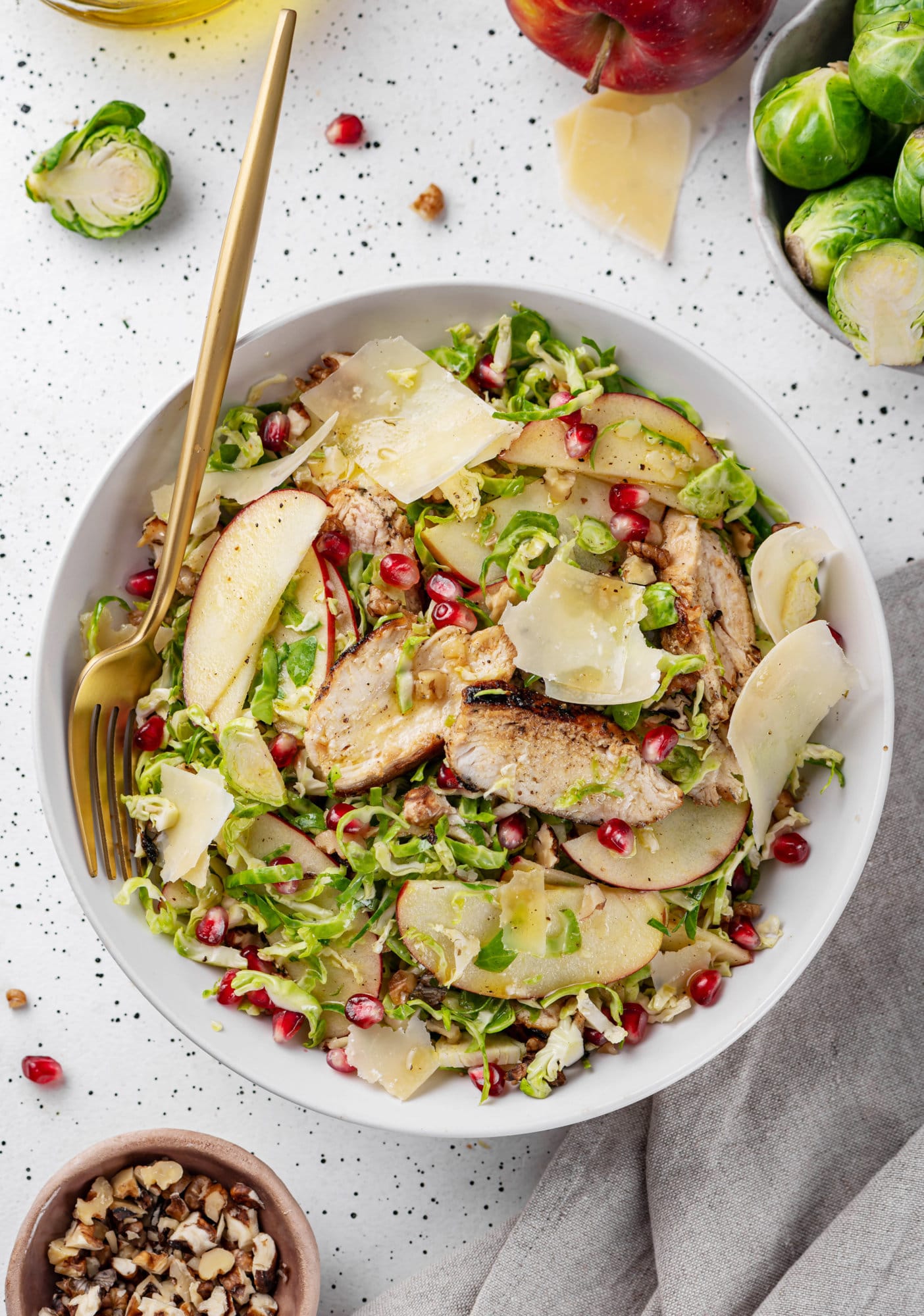 A brussels sprouts salad in a white bowl with a gold fork. 