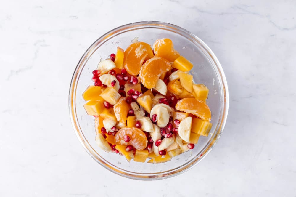 Persimmon fruit salad mixed in a glass bowl.