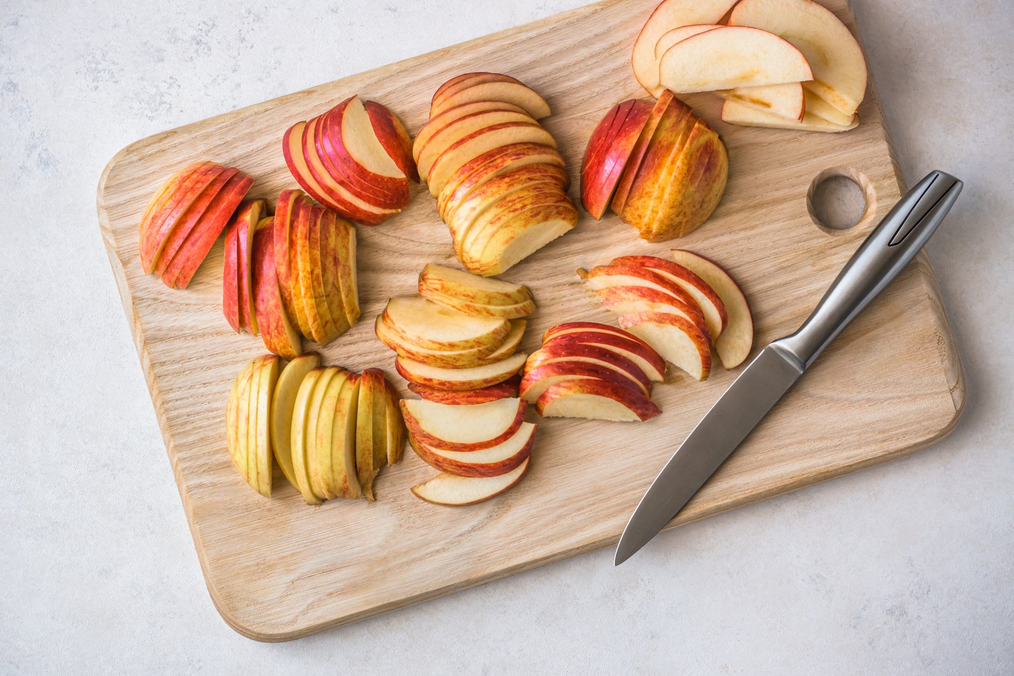 Sliced apples on a wooden cutting board with a knife. 